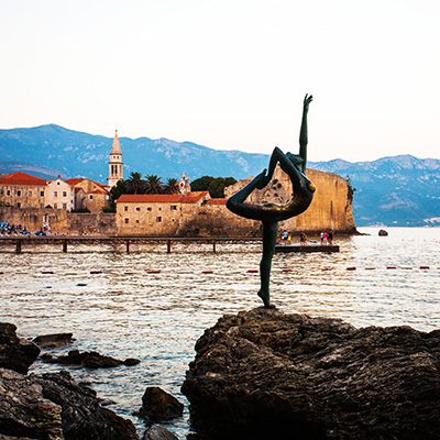 Dancer statue on the rocks below the old town of Budva, Montenegro