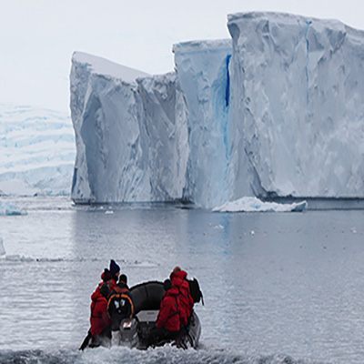 Zodiac beneath a towering Antarctic iceberg