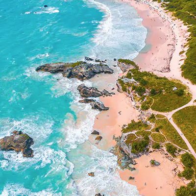 Pink-sand coves and turquoise water along a rocky island coast