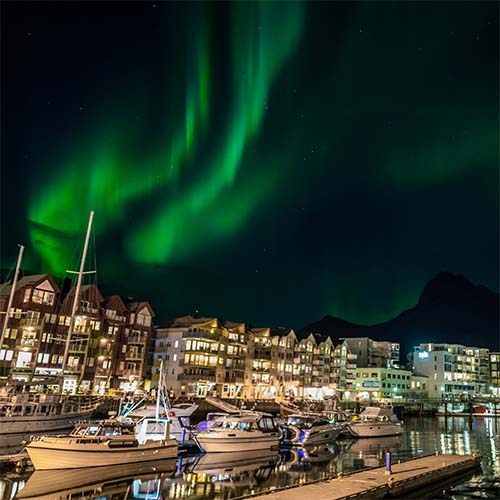 Northern lights over a Norwegian harbour town at night
