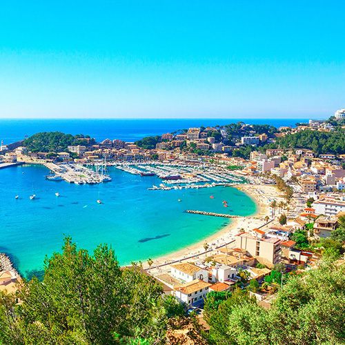 Mediterranean harbour town and beach below green hills